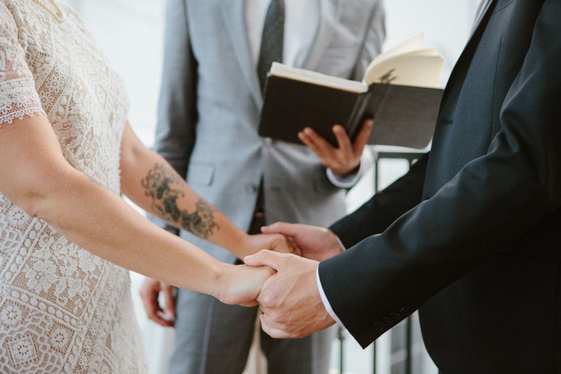 a close up photo of a couple holding hands in front of jacob during a ceremony